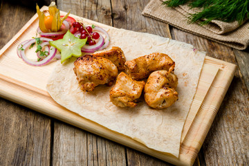 chicken kebab on board on wooden table
