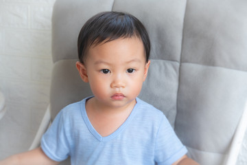 Adorable little boy sitting on big chair isolated,Smiling little boy sitting on stool.The little boy is lying.On a chair