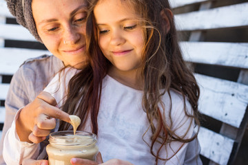 Family eating homemade peanut butter with finger, Mother and child, kid daughter. Vegan food.