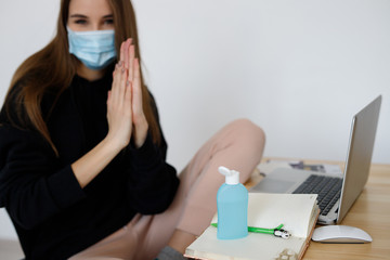Working from home, cleaning her hands with sanitizer gels, Woman in quarantine for coronavirus wearing protective mask.