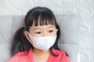 Little girl wearing mask for protect pm2.5 and Covid-19,sadness child at home in isolation,Coronavirus and Air pollution pm2.5 stop corona virus outbreak.Wuhan coronavirus and epidemic virus symptoms.