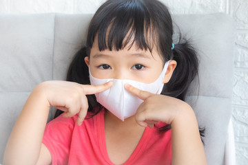 Little girl wearing mask for protect pm2.5 and Covid-19,sadness child at home in isolation,Coronavirus and Air pollution pm2.5 stop corona virus outbreak.Wuhan coronavirus and epidemic virus symptoms.
