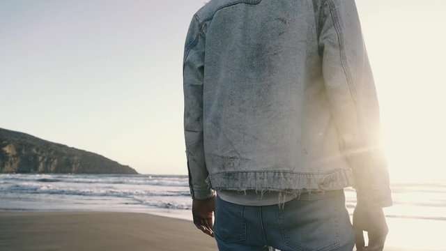 Man on the beach looking at the sea at sunset