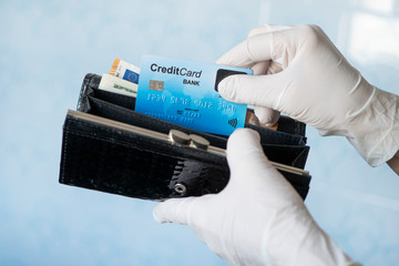 woman taking money out female wallet wearing rubber gloves to prevent the spread of bacterias or...