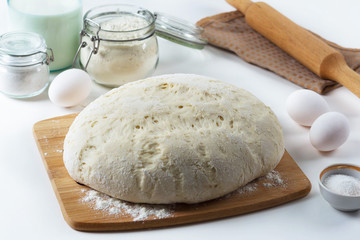 the dough lies on the table, next to a wooden rolling pin, flour and ingredients, pastries