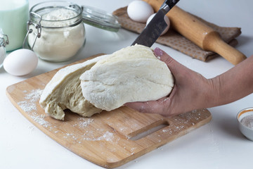 a woman cuts the dough with a knife on the table, next to the ingredients, bakes