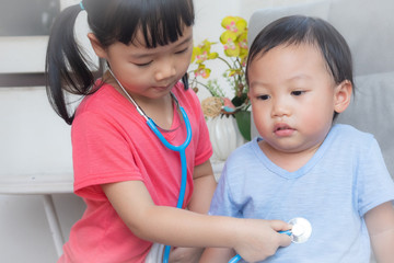 Little girl playing a doctor,boy and girl playing doctor and patient isolated,Two children play doctor and hospital using stethoscope,Sister and brother having fun at home or preschool,Tool doctor.