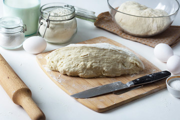 the dough lies on the table, next to a wooden rolling pin, flour and ingredients, pastries