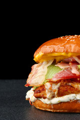tasty burger with chicken on dark isolated background. Homemade hamburger or burger with fresh vegetables and cheese