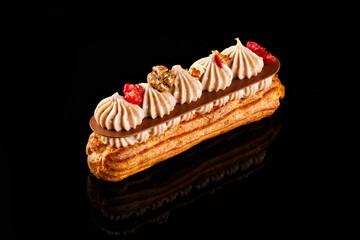 Eclair with cream filling and cranberry on top. Two layer of chocolate whip cream. Confectionary...