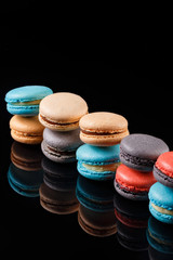 Assorted macaroons with flavorsome cream filling for all occasions. Confectionery photography concept in black background. Reflection