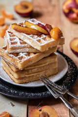 gebackene Waffeln mit Puderzucker und Früchten auf Brettern aus Holz mit schwarzem Hintergrund