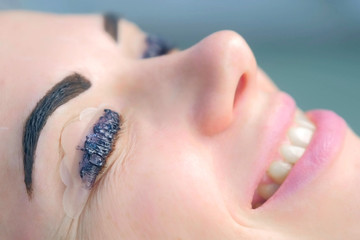 Portrait of woman on lash lifting laminating and eyebrow painting, side view. Waiting time lying on...