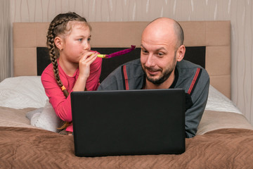 A little girl prevents dad from working on his laptop in the bedroom. Family is quarantined at...