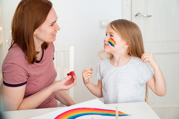 mom draws child of rainbow on cheek. stay home.