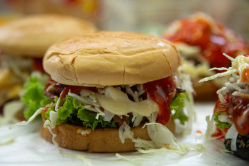 hamburger fast food  meal delicious American in the  restaurant, burger  Decorated with onion cherry tomatoes, Close-up of homemade tasty burgers on wooden table, Craft beef burgers with vegetables

