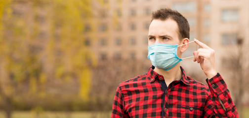 Young handsome man wearing face pollution mask to protect from coronavirus walking alone outdoor by city street