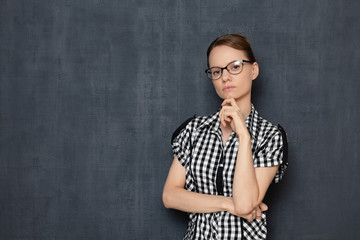 Portrait of focused girl with glasses, touching chin with hand