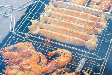 fresh juicy shish kebab sausages and prawns fried on coals on a barbecue in the backyard