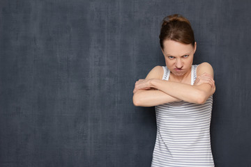 Portrait of funny angry girl with holding arms crossed on chest