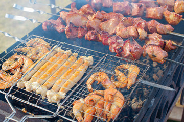 fresh juicy shish kebab sausages and prawns fried on coals on a barbecue in the backyard