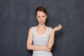 Portrait of serious focused girl wearing taking off her glasses