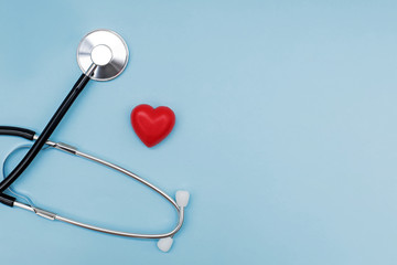 Stethoscope with red heart on blue background with copy space.