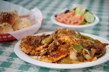 Chicken pasta topped with bell peppers onions and mushrooms with garlic rolls and salad
