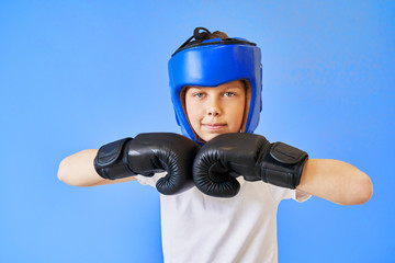 a boy with green eyes wearing a Boxing helmet and gloves on a blue background