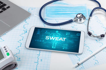 Tablet pc and doctor tools with SWEAT inscription, coronavirus concept