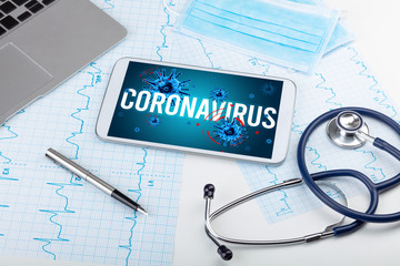 Tablet pc and doctor tools on white surface with CORONAVIRUS inscription, pandemic concept