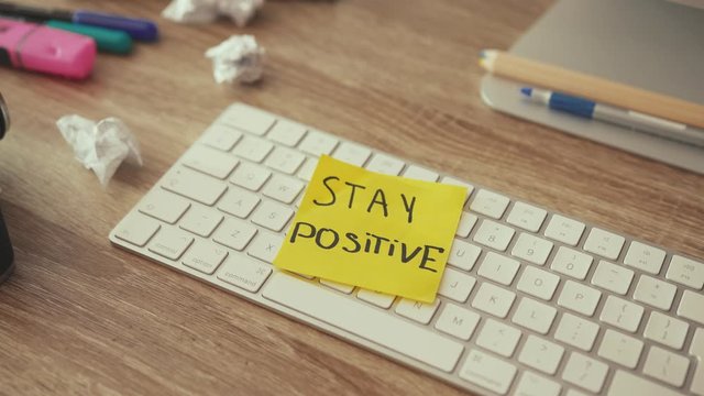 Freelancer home office desktop table. Close-up keyboard with Stay Positive motivation text note. Artists mess. Business, inspiration, motivation.
