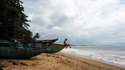 Brunette woman sit on traditional wooden fishing boats in a tropical beach of Sri Lanka