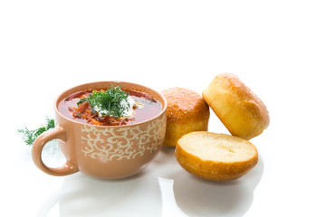 hot beetroot soup with sour cream, herbs and rolls in a ceramic bowl