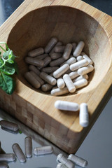 Fototapeta na wymiar Pills in a wooden mortar. Treatment with tablets