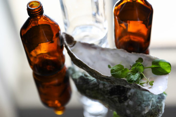 Brown transparent bottles with green sprouts on a mirrored table