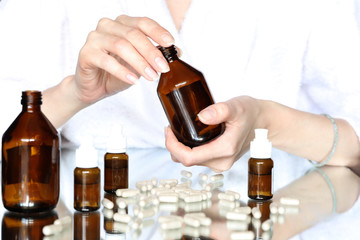 Women sitting at the table holding a bottle of dark glass, close up. Cosmetics and Science