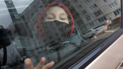 a boy in a black mask behind a car window