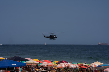 Police helicopter flying over crowded beach in Rio de Janeiro Brazil