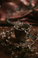 black tea with flowers and blooming  branch on wooden background