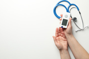 Female checking blood sugar level on white background