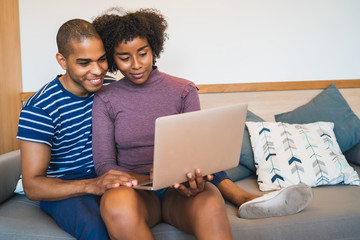 Young couple using laptop on couch at home.