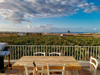 Beautiful  view of wooden table and barbecue kitchen grill ready to host people to have un together - nature and home concept - blue sky and ocean in background