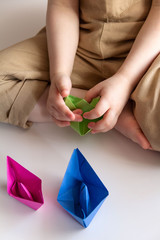 child plays with colored paper boats