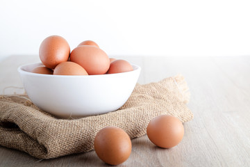 Many organic chicken eggs are placed in a white bowl on a wooden floor. Food concepts that are beneficial to the body provide high energy. copy space