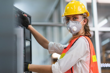 Female Engineer wear face mask with safety vest and yellow helmet operating control CNC Machinery...