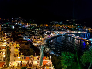 Aerial panoramic cityscape view of Parga city, Greece during the Summer. Beautiful architectural colorful buildings illuminated at night and night traffic near the port of Parga Epirus, Greece, Europe