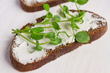 Healthy macrobiotic breakfast. Sandwich with cream cheese and peas microgreens.