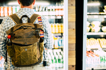 Travel man viewed from back in front of an automatic drink store choosing snacks or beverage before...