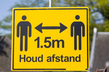 Yellow warning sign with the text in dutch: 1.5 meter, keep distance